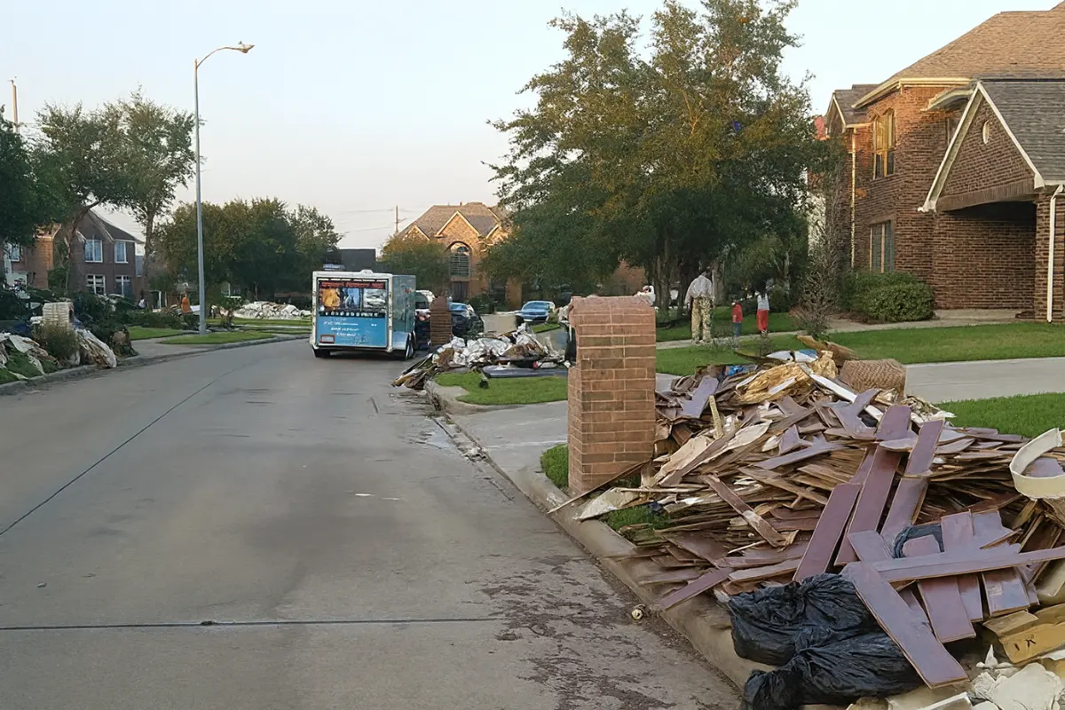 Piles of damaged wood, soaked debris, and household materials stacked curbside after severe flooding, illustrating large-scale flood cleanup efforts in New Jersey.