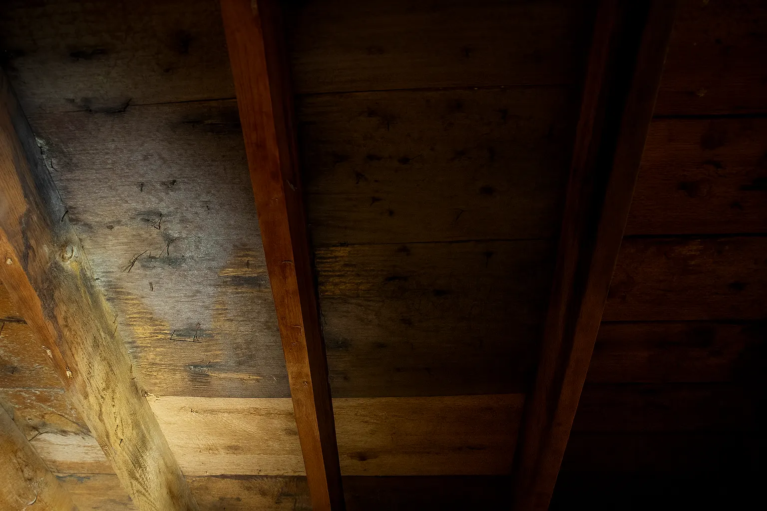 Close-up view of exposed wood joists with discoloration and moisture staining, captured during a water damage inspection in New Jersey.