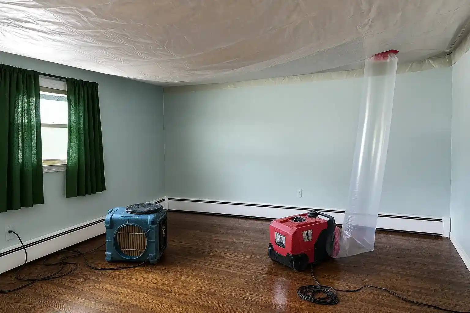 Room with drying equipment, plastic ceiling containment, and ventilation tubing used during a water damage restoration service in NJ.